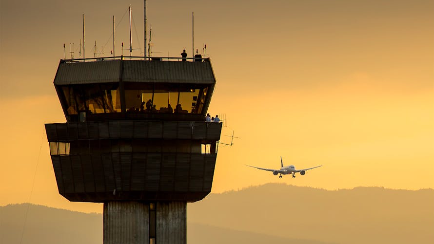 Tour de contrôle d'aéroport avec un avion approchant au coucher du soleil